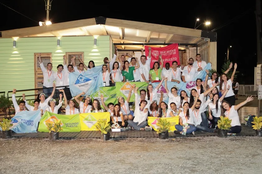 Equipe da Casa Minga reunida em frente à casa, à noite, com bandeiras